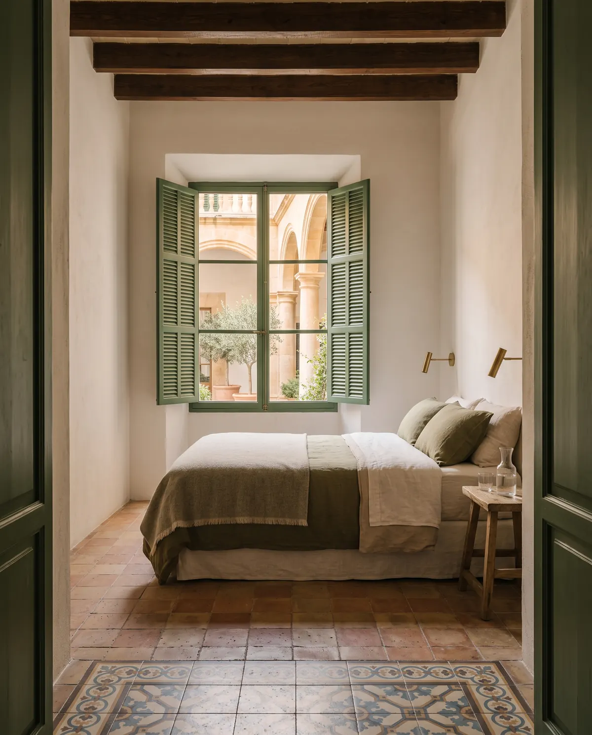 The bed of the Courtyard Room seen through the door, with the window onto the courtyard behind it