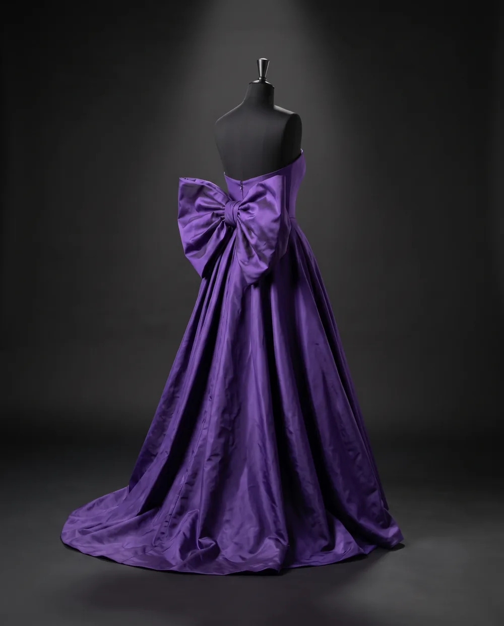 The Bow Gown on a black dress form: a strapless violet taffeta gown with a large bow