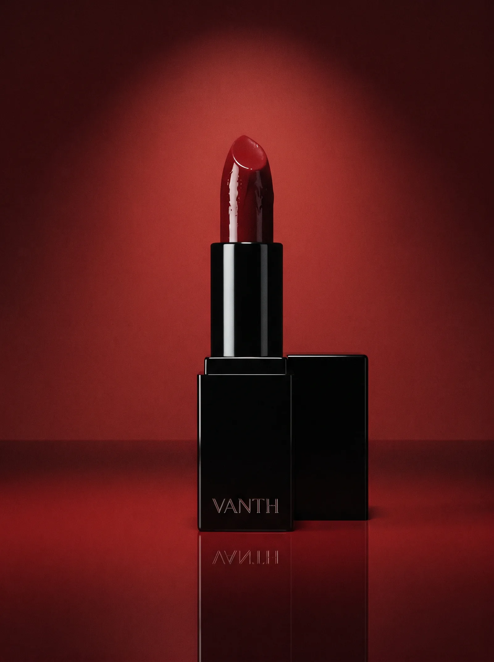 The Lacquer Red lipstick open and upright on red lacquer: a square case of glossy black lacquer with VANTH engraved in silver, a deep red bullet with a wet shine and the black cap standing behind it